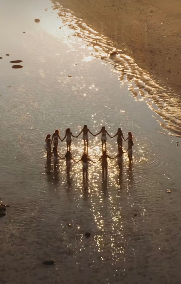 Women holding hands in a circle in shallow water