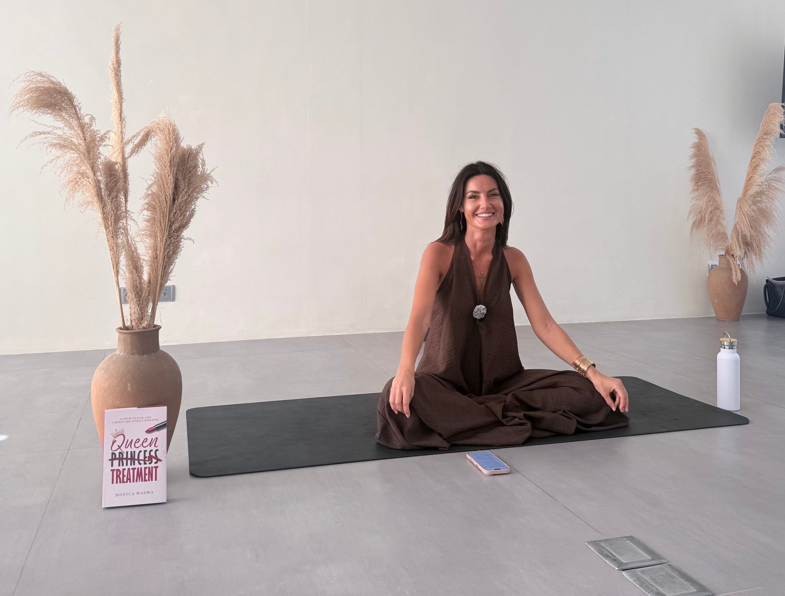 Monica seated in meditation with a copy of her book Queen Treatment