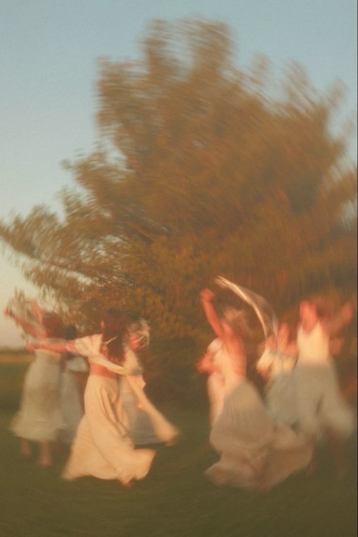 Women dancing in white dresses at golden hour